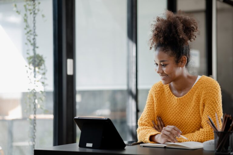 American teenage woman sitting in office with laptop.